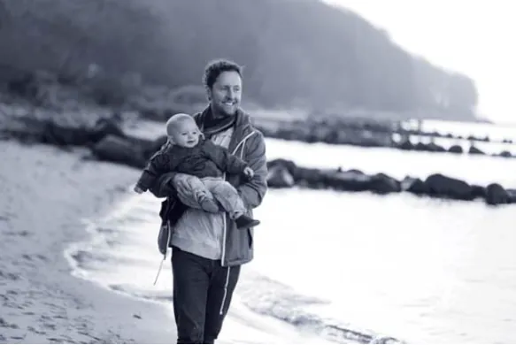 Un padre con il figlio in braccio in riva al mare: l’idea di ambiente protetto